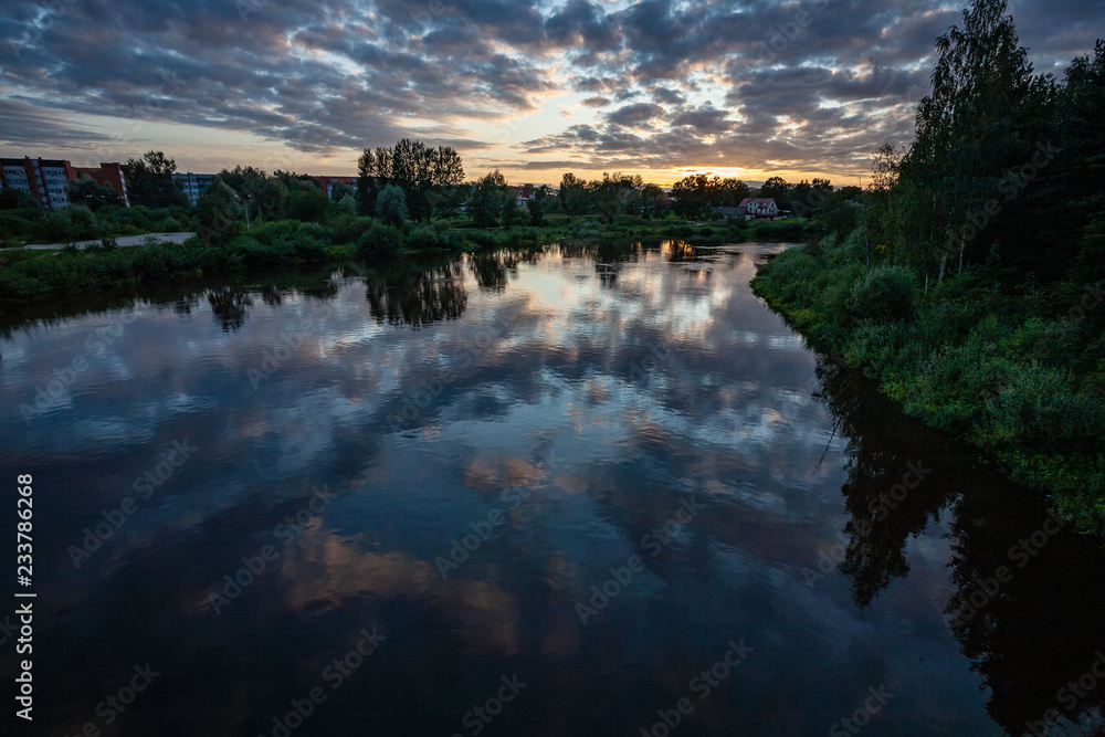 Obraz premium colorful sunset on the lake with water reflections and dramatic storm clouds above