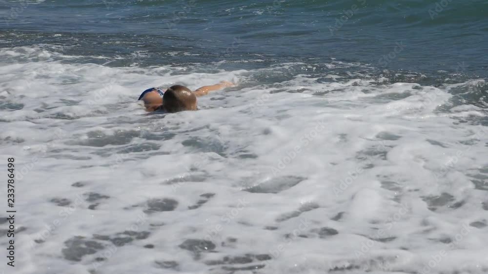 baby on the beach, in the maritime wave. little boy in black glasses for scuba diving dives under the sea wave. baby on the beach, in the maritime wave. little boy in black glasses for scuba diving dives under the sea wave.