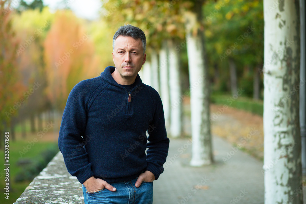 Handsome middle-aged man walking autumn park. Urban male portrait, image toned and noise added. Handsome middle-aged man walking autumn park. Urban male portrait, image toned and noise added.