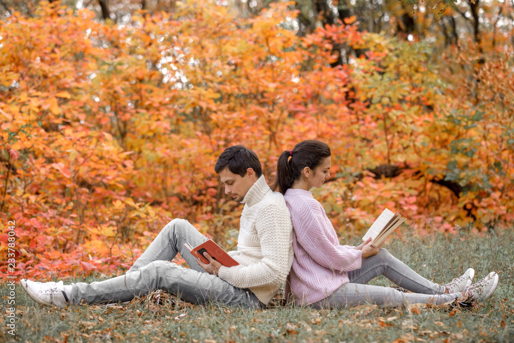 couple in love sitting in autumn park and reading book couple in love sitting in autumn park and reading book