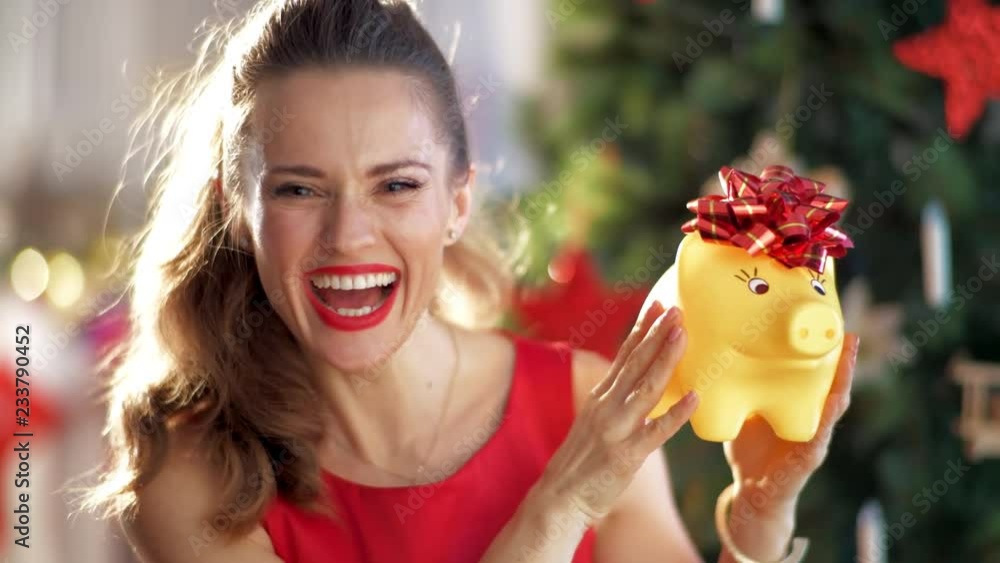 happy stylish woman in red dress with yellow piggybank near Christmas tree New Year - time for gifts. Start of new fiscal year with happy piggybank!. This video was shot in PRORes 422 codec. happy stylish woman in red dress with yellow piggybank near Christmas tree New Year - time for gifts. Start of new fiscal year with happy piggybank!. This video was shot in PRORes 422 codec.