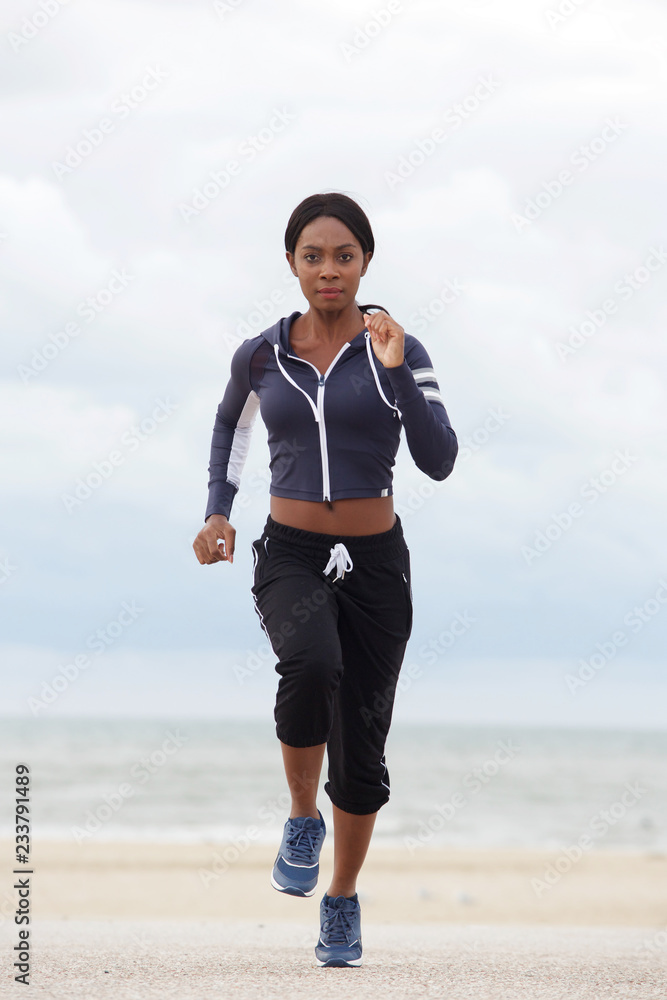 Full body healthy african american woman running at the beach Full body healthy african american woman running at the beach