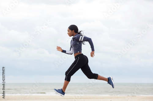 side portrait of african american woman running by the beach