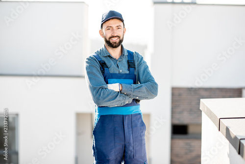 Foto Portrait of a builder in uniform on the roof of a new white building outdoors