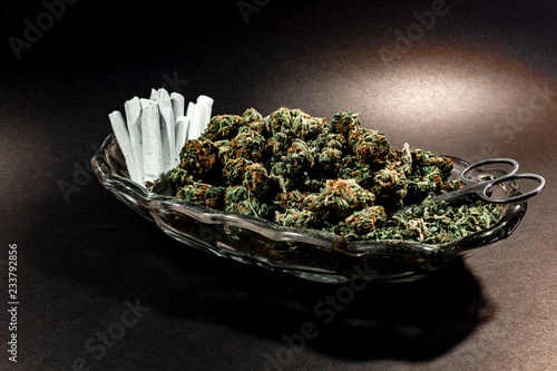 Obraz na płótnie Classy glass dish with marijuana bud, scissors and a dozen joints on black with spot lighting w salonie