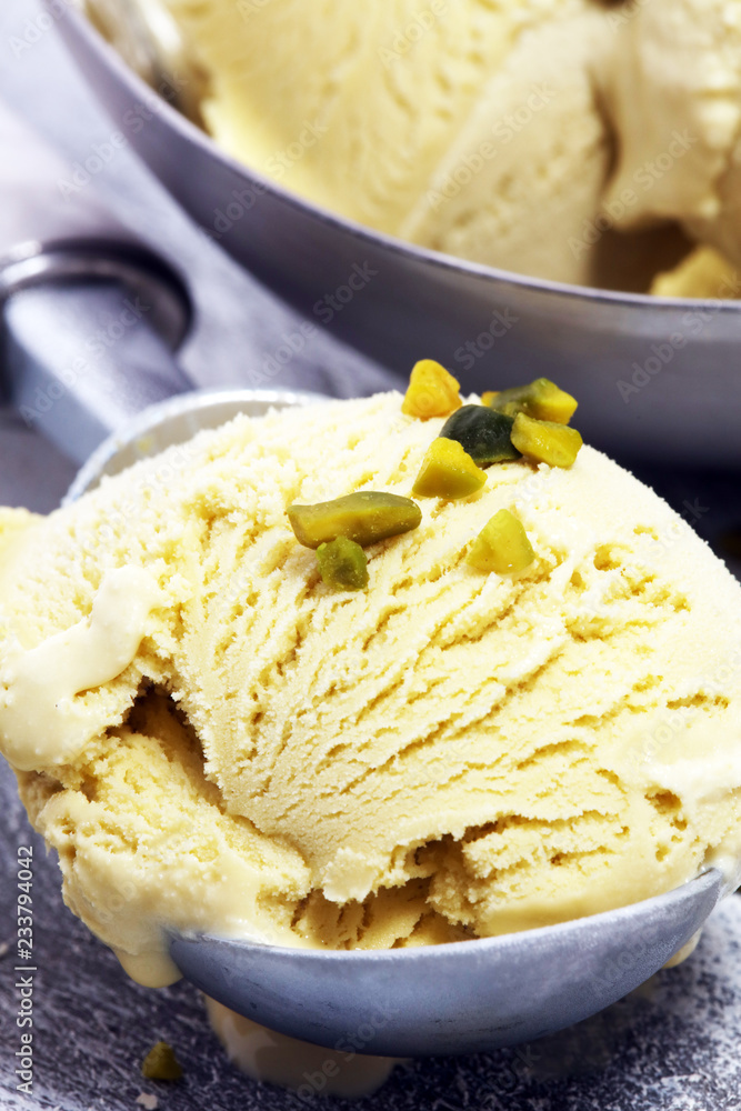 Pistachio ice cream scoop with chopped nuts and white chocolate on a rustic background. Pistachio ice cream scoop with chopped nuts and white chocolate on a rustic background.