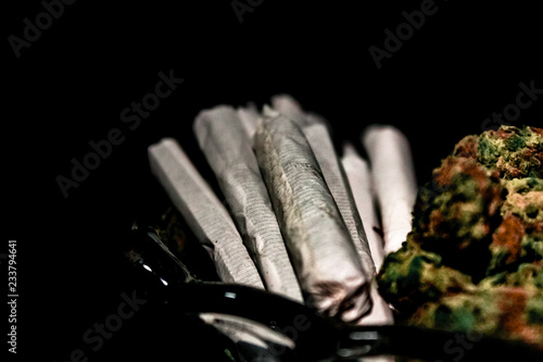Obraz na płótnie A handful of joints in the end of a glass dish next to a pile of marijuana bud isolated in black. w salonie
