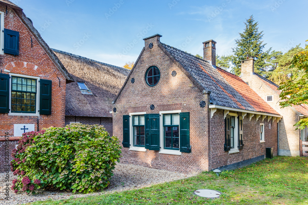 Idyllic Dutch farmhouse with black red roof tiles and green shutters