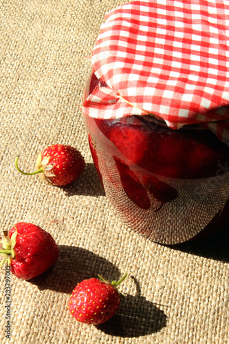 jar with strawberry jam and berries on the sacking