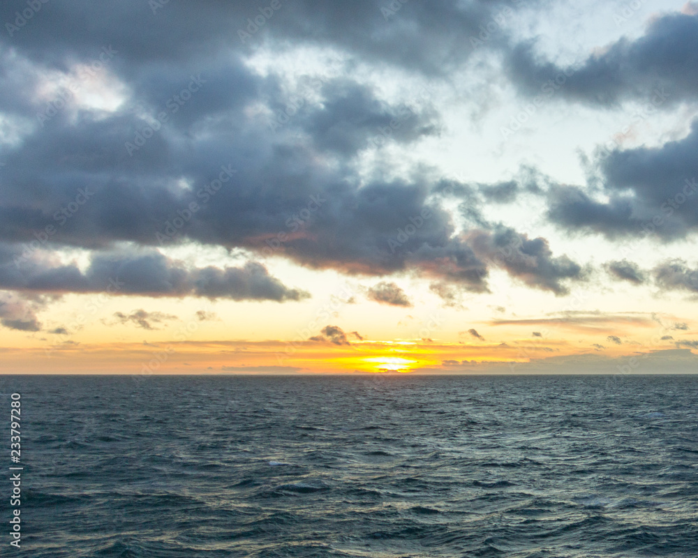A sunset at sea with dramatic puffy clouds