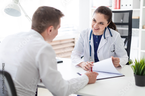 The young man at the doctor's office signs the documents. © Ivan Traimak