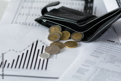 Fotografia The black wallet with coins are on tax papers and finances diagram