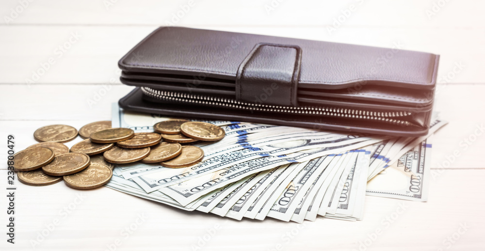Black purse with dollar bills and coins on wooden table. Toned image. Black purse with dollar bills and coins on wooden table. Toned image.