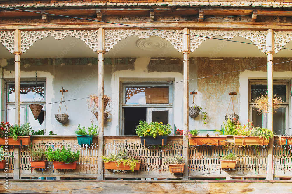 Old House in Tbilisi, Georgia with Beautiful Terrace. Ancient traditional wooden balcony decorated with lot of flowers and old artifacts