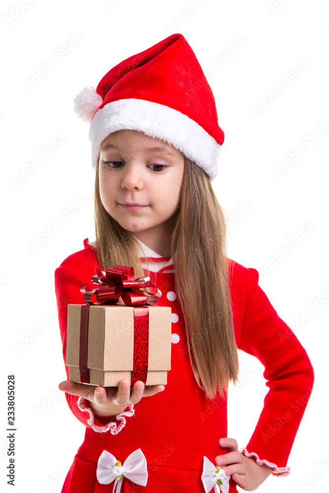 Happy christmas girl looking at the gift holding it in the hand, wearing a santa hat isolated over a white background