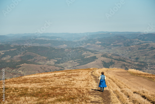 Man traveler walking along the road. There are mountains on the horizon. The sky is blue and cloudy.