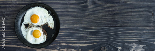 fried eggs on a cast-iron pan on an old wooden gray background