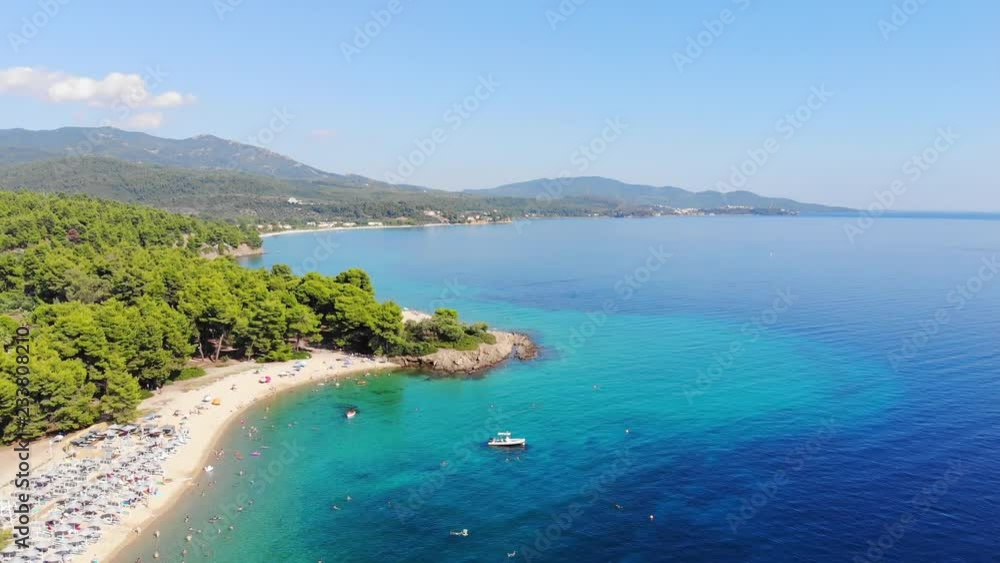 Aerial view of beautiful sandy beach, people sunbathing and swimming. Drone shot flying over Lagomandra beach in Sithonia, Greece