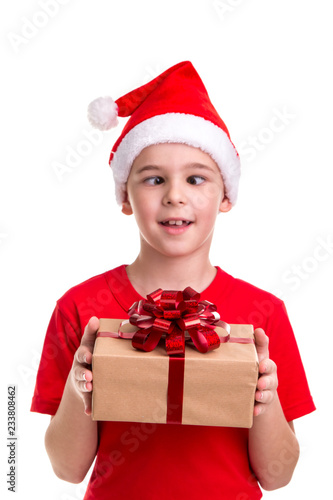 Funny boy, squint eyes, santa hat on his head, with the gift box in the hands. Concept: christmas or Happy New Year holiday
