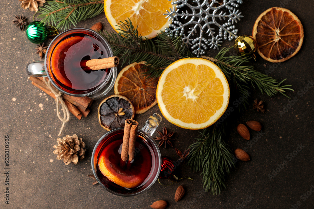 Hot mulled wine with cinnamon and orange in glass cups and Christmas decorations on a dark background. View from above. Christmas. new Year. Hot mulled wine with cinnamon and orange in glass cups and Christmas decorations on a dark background. View from above. Christmas. new Year.