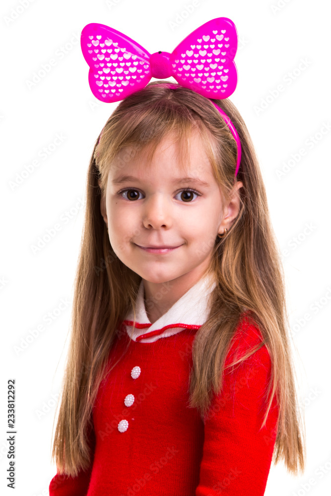 Happy little smiling blond girl in a red dress with a pink band bow on the white isolated background. Happy little smiling blond girl in a red dress with a pink band bow on the white isolated background.