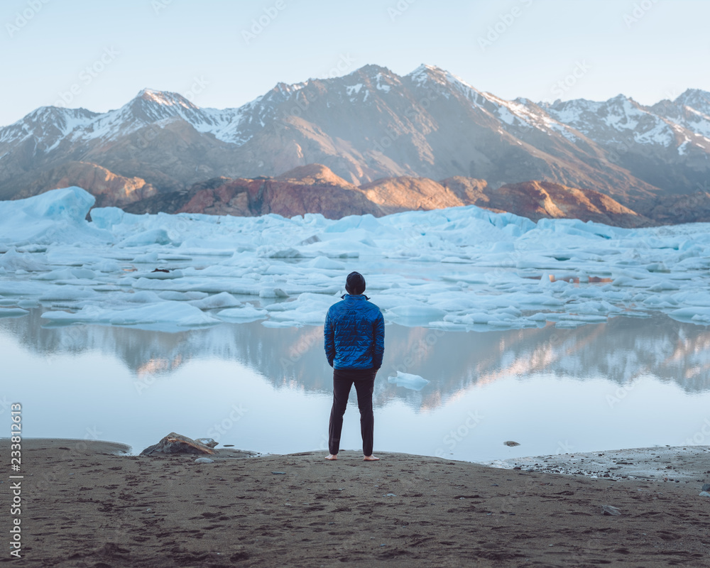 Man looking at a calm lake with icebergs Man looking at a calm lake with icebergs