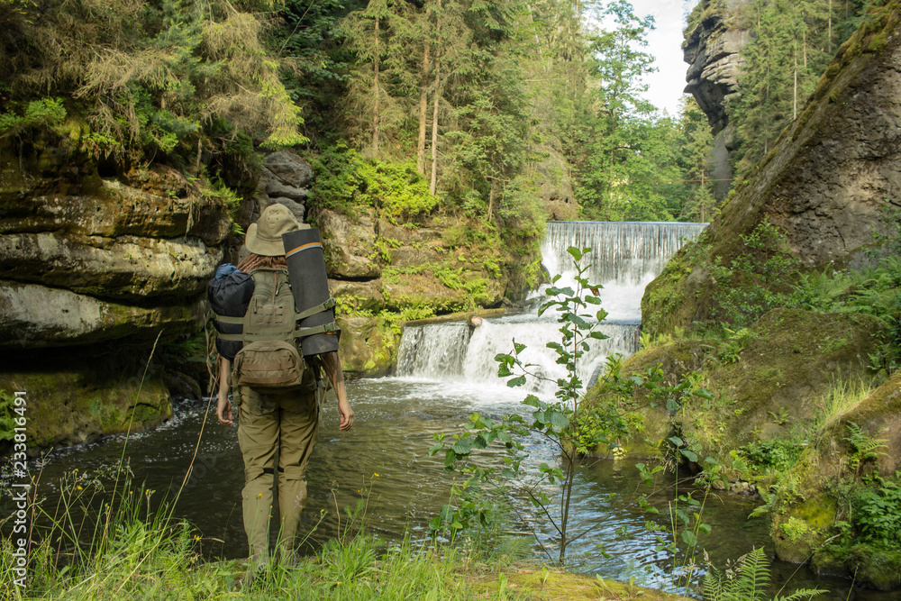 Young woman hiker posing near the river in bohemian switzerland national park, female traveler in mountains of czech republic