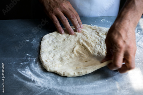 Close up of man's hand patting out pizza dough photo