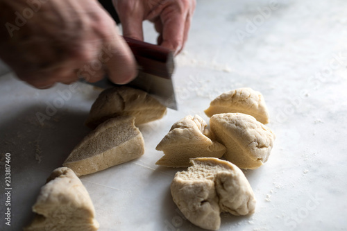 Close up of man cutting dough with dough scraper