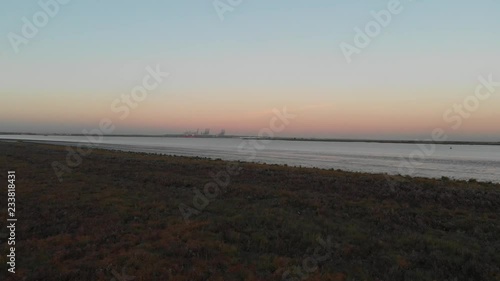 An low altitude shot over marsland and bushes with the DP World London Gateway Port in the background photo