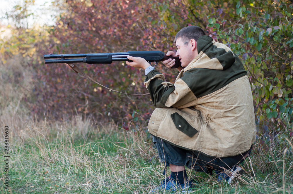 Fototapeta premium A man hunter is in position and preparing to make a shot from a gun.