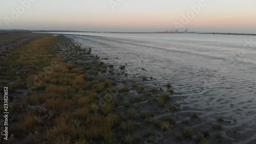 An aerial shot of the vegetation and mudflats of Thames estuary at low tide with the DP World London Gateway Port in the background photo