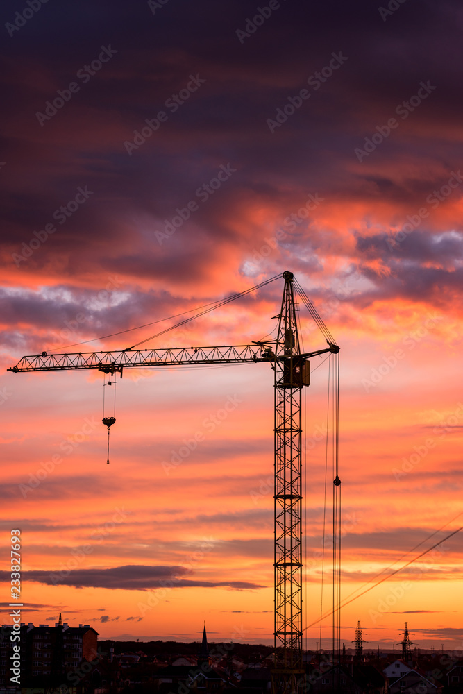 Boom crane on the background of fiery sunset sky, a part of industrial construction, vertical image Boom crane on the background of fiery sunset sky, a part of industrial construction, vertical image