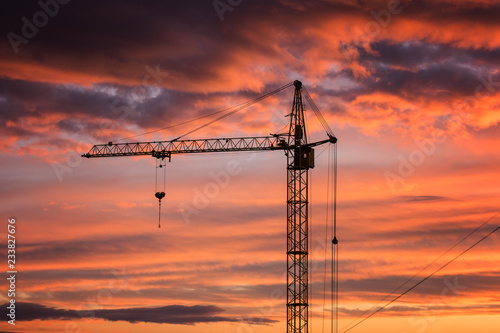 Boom crane on the background of fiery sunset sky, a part of industrial construction