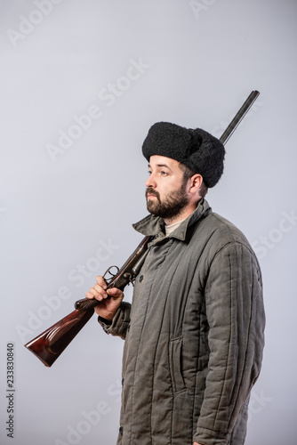 Hunter with a rifle on his shoulder, old-fashioned clothes, studio shot photo