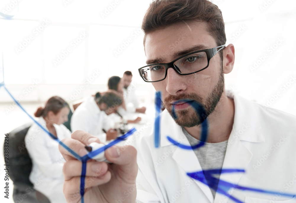 from behind the glass.scientist writes a marker on a glass Board. from behind the glass.scientist writes a marker on a glass Board.