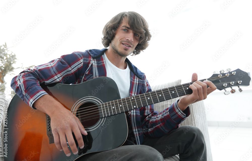 Fototapeta premium guy sings a song and plays guitar sitting on the couch.