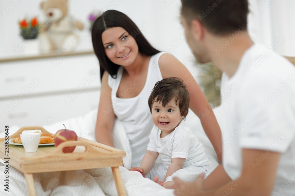 Family taking the breakfast on the bed in the bedroom Family taking the breakfast on the bed in the bedroom