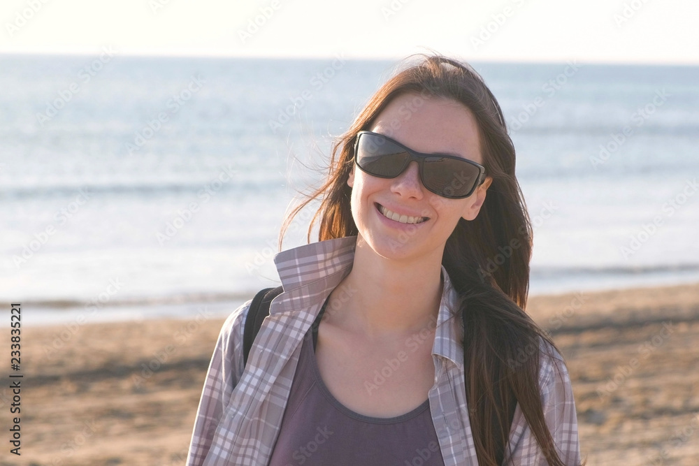 Happy young smiling brunette woman in sunglasses at sand beach by the sea. Happy young smiling brunette woman in sunglasses at sand beach by the sea.