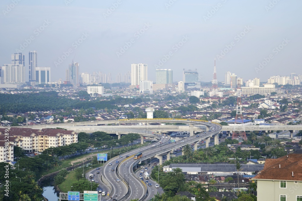 Aerial view of Johor Bahru's cityscape with highways and vehicles on a hazy foggy morning 