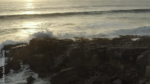 4k footage - Aerial / drone view of a surf surfer trying to get on water on a dangerous place. Surfer tries to go but a big wave makes him think twice of the danger.