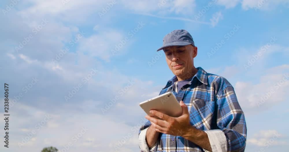 Farmer using digital tablet at farm against blue sky and clouds. Farmer using digital tablet at farm against blue sky and clouds.