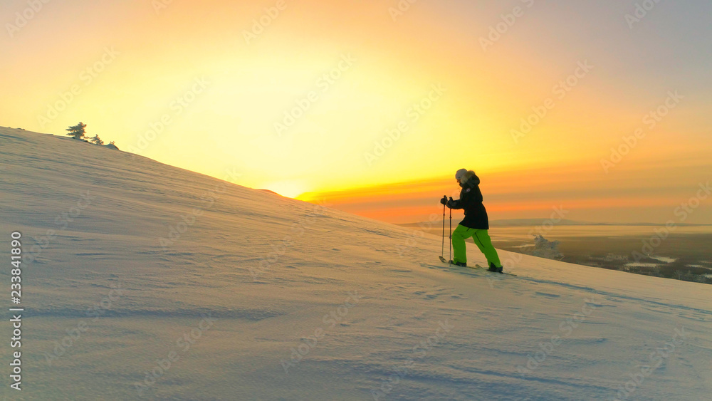 AERIAL: Active woman snowshoe trekking on snowy mountain slope at winter sunset AERIAL: Active woman snowshoe trekking on snowy mountain slope at winter sunset