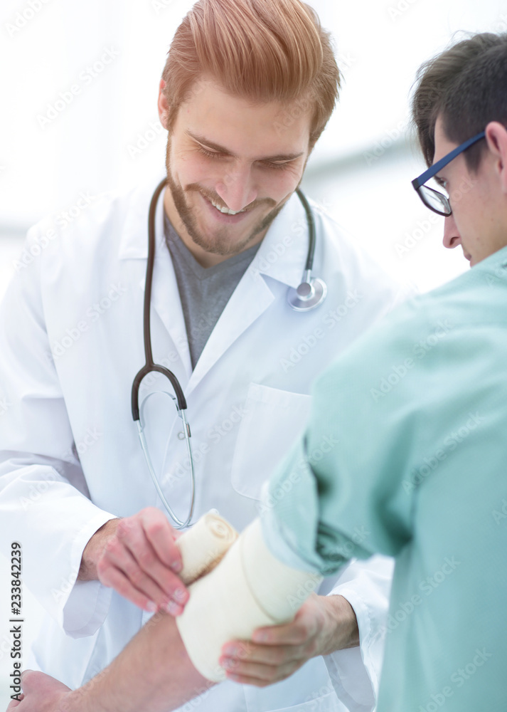 Orthopedist applying bandage onto patient's arm Orthopedist applying bandage onto patient's arm