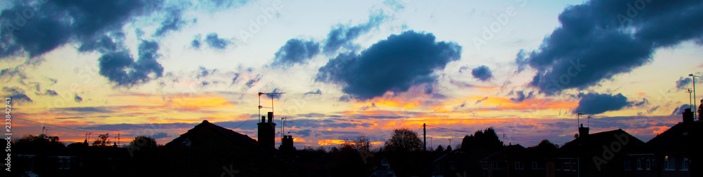 An urban sunset panorama with houses in silhouette An urban sunset panorama with houses in silhouette