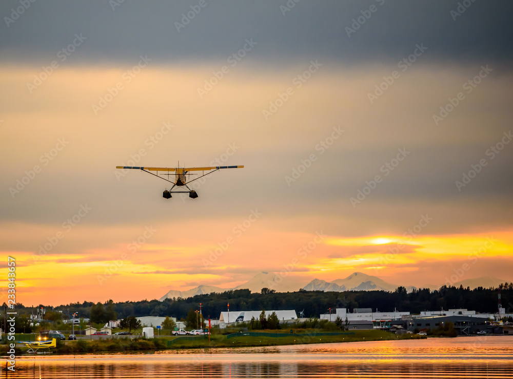 Sunset Over a Lake in Anchorage Alaska with a Float Airplane Taking off in the Distance