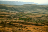 Haze covered the sky and hilly valley with autumn fields located in the mountains Geghama ridge
