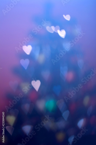 Defocused Christmas tree with heart shaped bokeh. Festive holiday background. 