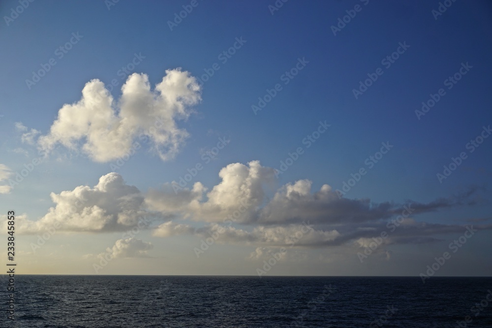 Thick white clouds over the horizon in a deep blue sky somewhere in the North Pacific Ocean between Sitka, Alaska, and Victoria, British Columbia, Canada. Thick white clouds over the horizon in a deep blue sky somewhere in the North Pacific Ocean between Sitka, Alaska, and Victoria, British Columbia, Canada.