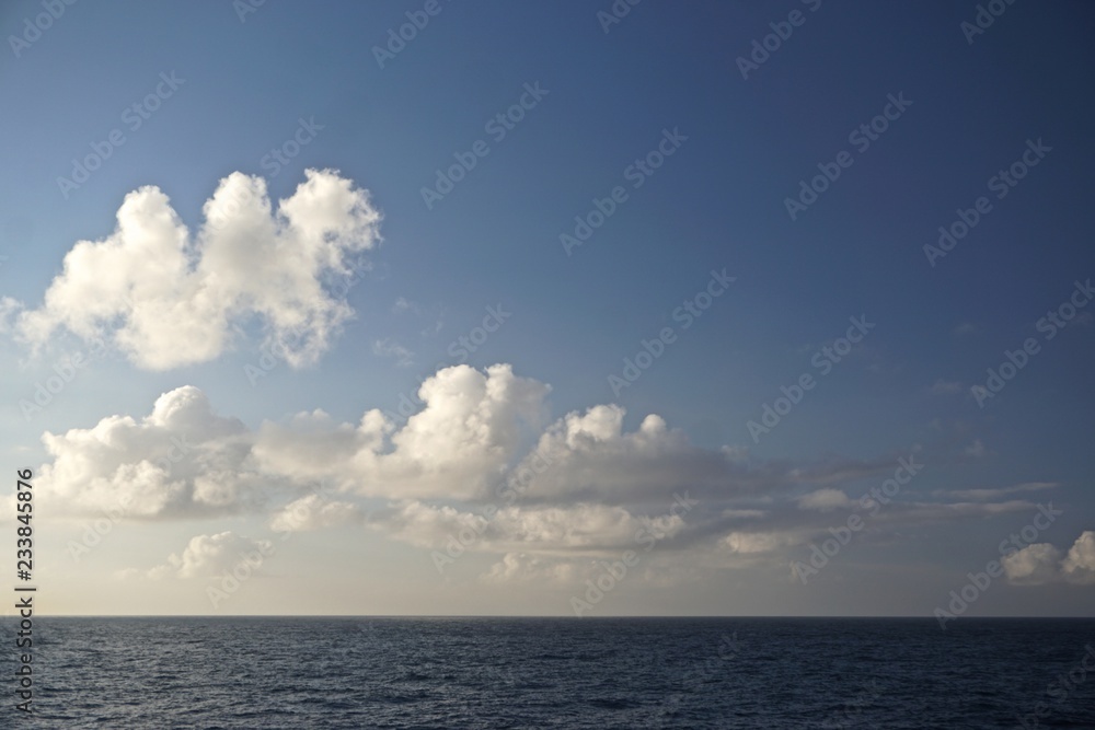 Thick white clouds over the horizon in a deep blue sky somewhere in the North Pacific Ocean between Sitka, Alaska, and Victoria, British Columbia, Canada.
